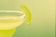 Close up of a lime wedge on salt rim of margarita glass isolated on pale green pastel color background with room for text.