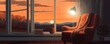 Warm-hued sunset visible through large windows with a solitary armchair and reading materials, evoking tranquility and a homely feel
