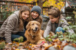 Cheerful, friendly, smiling family, parents with children playing with their pet red Labrador breed dog in the fall in the yard of their house.