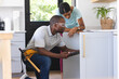 © Wavebreak Media - African American plumber fixing sink while using tablet while homeowner is watching