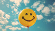 © JulMay - Bright yellow balloon with a smiley face against a blue sky with clouds, symbolizing happiness and positivity.