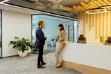 Fototapeta Las - Professional Colleagues Engage in Conversation by the Reception in a Modern Office Setting