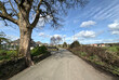 © derek oldfield - A scenic country road, meanders gently under a bright blue sky with scattered clouds, flanked by bare trees and a stone wall on, Spen View Lane, Bradford, UK