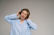 Listening enjoying music. Blonde singing woman with headphones dancing. Studio shot. Gray plain background. Music lover theme banner with copy empty space
