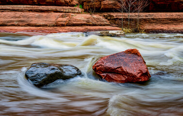 Wall Mural - Water rushes by gray and red boulders in Oak Creek at Slide Rock State Park near Sedona Arizona