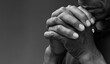 © herlanzer - man praying to god with hands together Caribbean man praying with grey black background stock photo