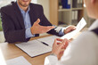 © Studio Romantic - Close up cropped photo of a young business people working in office in suit. Company employees sitting at the desk and looking through documents on workplace discussing work project.