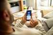 © Davor - Man checking bank account on smartphone at home