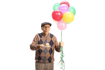 Wall Mural - Elderly man holding a birthday cupcake with a candle and a bunch of balloons