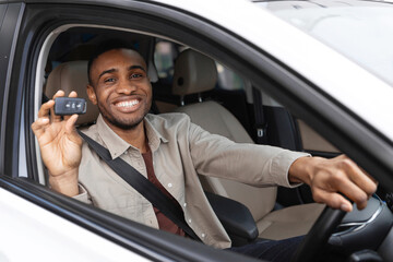 Wall Mural - Joyful african american guy holding auto key shaking fists sitting in automobile 