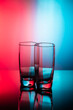 Drinking transparent glasses on a colored background with reflection.