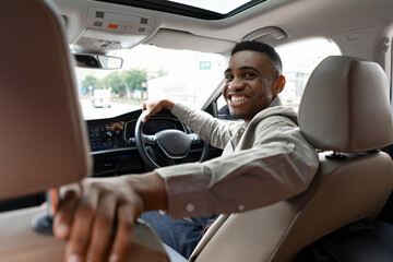 Wall Mural - Joyful African American Man Smiling Sitting In Automobile Looking Back At Camera