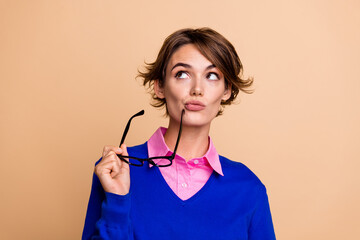 Sticker - Portrait of intelligent creative girl hold eyeglasses look empty space ponder isolated on beige color background