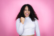 African american woman wearing casual sweater over pink background angry and mad raising fist frustrated and furious while shouting with anger. Rage and aggressive concept.