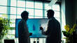 Two healthcare professionals engrossed in examining a growth chart on a large monitor in a conference room, their silhouettes framed against the bright daylight that fills the room