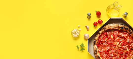 Wall Mural - Delicious pepperoni pizza in cardboard box and ingredients on yellow background with space for text, top view