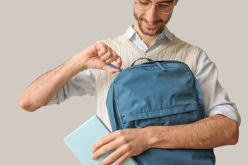 Sticker - Male student with backpack and book on light background, closeup