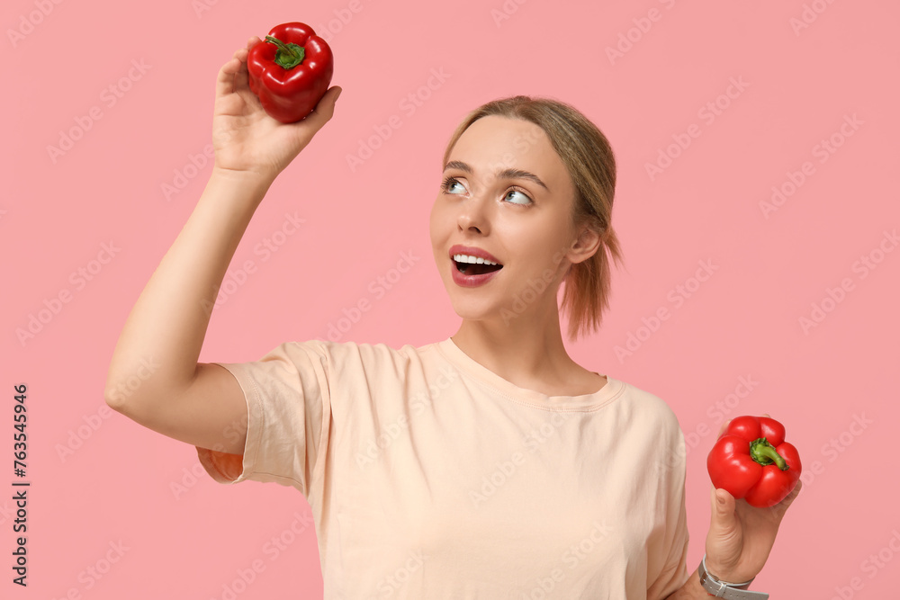 Young woman with bell peppers on pink background