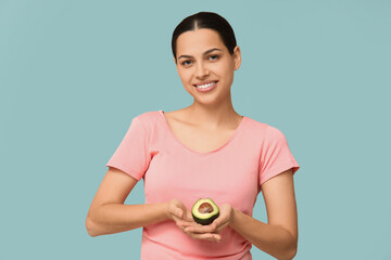 Poster - Pretty young woman with fresh avocado on blue background