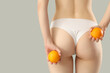 © Pixel-Shot - Young woman in underwear with oranges on grey background, back view. Concept of cellulite