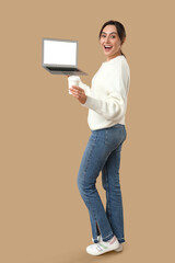 Poster - Pretty young woman holding laptop with blank screen and takeaway cup of coffee on beige background