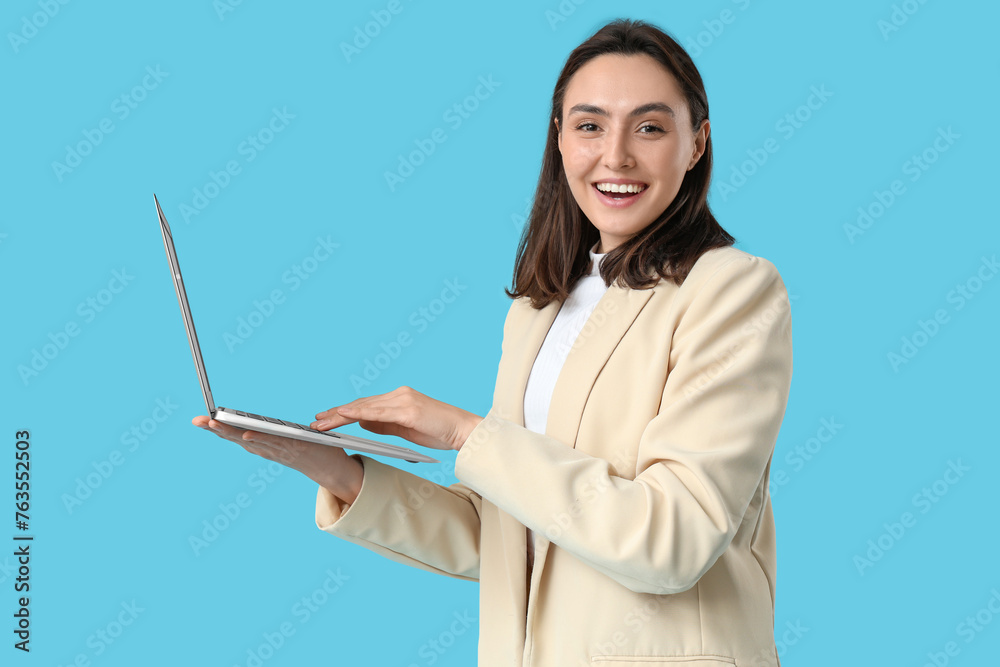 Young businesswoman with laptop on blue background