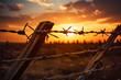 In the intimate focus of the lens, the intricate details of a barbed wire fence are starkly outlined against the canvas of a resplendent sunset casting a poignant juxtaposition of beauty & confinement