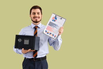 Wall Mural - Happy young man holding safe box and clipboard with graphics on green background