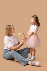 Wall Mural - Little girl giving flower to her mother on beige background. Mother's Day