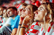 A group of male and female Croatian football fans sit in the stadium with very sad faces and distressed expression and Hands clasped together desperately over her heads after losing the game 