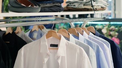 Panning shot of stylish formal clothes on hanger in empty fancy fashion boutique. Latest exquisite designer clothing men shirts collection in premium showroom, close up shot.