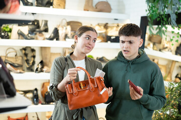 Wall Mural - Couple man and woman in casual clothes chooses handbag and wallet in store..