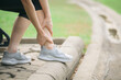 © Jirawatfoto - Sprained ankle problem. woman jogger. 30s asian female wearing sportswear holding her ankle with pain after running exercise in public park.