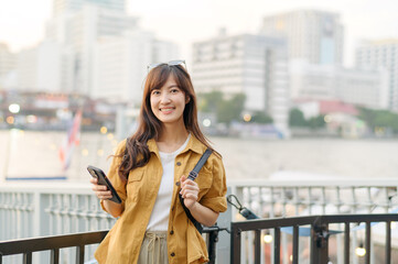 Wall Mural - young Asian woman in 30s on a solo adventure. Technology in hand, she captures the essence of cultural exploration and joyful discovery.