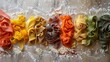 A row of colorful pasta is laid out on a table