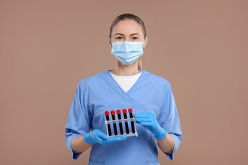 laboratory testing. doctor with blood samples in tubes on light brown background