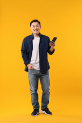 Poster - Full length portrait of happy man with smartphone on yellow background