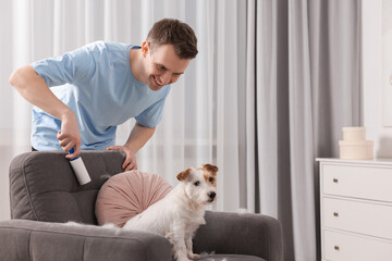 Sticker - Smiling man removing pet's hair from armchair at home. Space for text