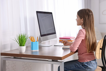 Wall Mural - E-learning. Girl taking notes during online lesson at table indoors