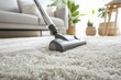 A vacuum cleaner is being used to clean a carpeted floor