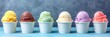 Assorted ice cream flavors in paper cups on a grey background.