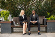 Black businessman sitting on a bench and talk with caucasian woman