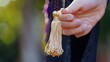 The tassel being held between two fingers ready to be flipped over to signify the end of one academic journey and the beginning of another.