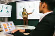 © artitwpd - A cheerful and confident Asian businesswoman stands, presenting bar charts data from the projector screen to his office colleagues. Asian businesswoman leader role at the meeting.