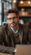 © Natalia - A man in glasses and a sweater is sitting at a table with a laptop. Generative AI.