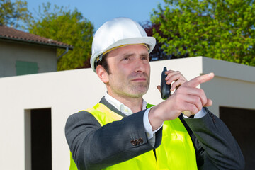 suited man wearing high-visibility vest using walkie-talkie