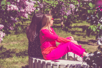 Wall Mural - Two girls are sitting on a bench in the botanical garden
