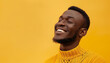A man with a big smile on his face is wearing a yellow sweater