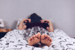 Bare feet of a teenage girl. The girl in pajamas lies on the bed covered with a blanket. Foot and heel