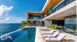 A modern beach house with an infinity pool and a balcony overlooking the ocean, with concrete accents and wooden details, with lounge chairs in front of it, and a blue sky